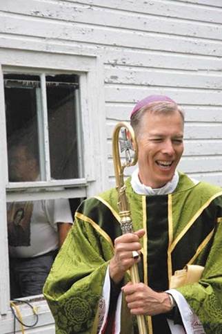 Archbishop Alexander Sample laughs before a 2012 Mass at a small historic chapel on Sugar Island, Mich.